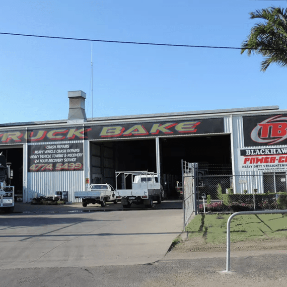 A truck with solar panels is parked in front of a building with a sign that says truck bakes.