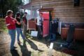 A group of people standing in front of a house powered by solar panels.