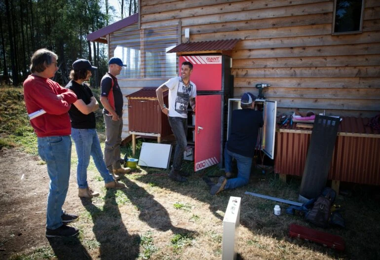 A group of people standing in front of a house powered by solar panels.