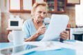 An elderly woman is looking at papers with a magnifying glass in Cairns.