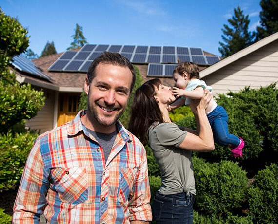 A family standing in front of a house with solar panels in Cairns.