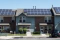 A row of houses with solar panels on their roofs, harnessing the benefits of solar power.