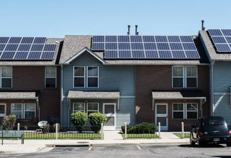 A row of houses with solar panels on their roofs, harnessing the benefits of solar power.