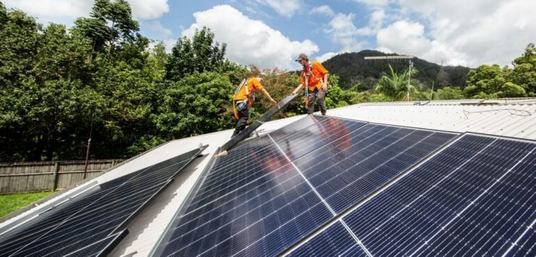Two men working on solar panels on a roof in Cairns for Hielscher Electrical.