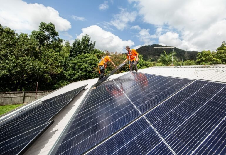 Two men working on solar panels on a roof in Cairns for Hielscher Electrical.