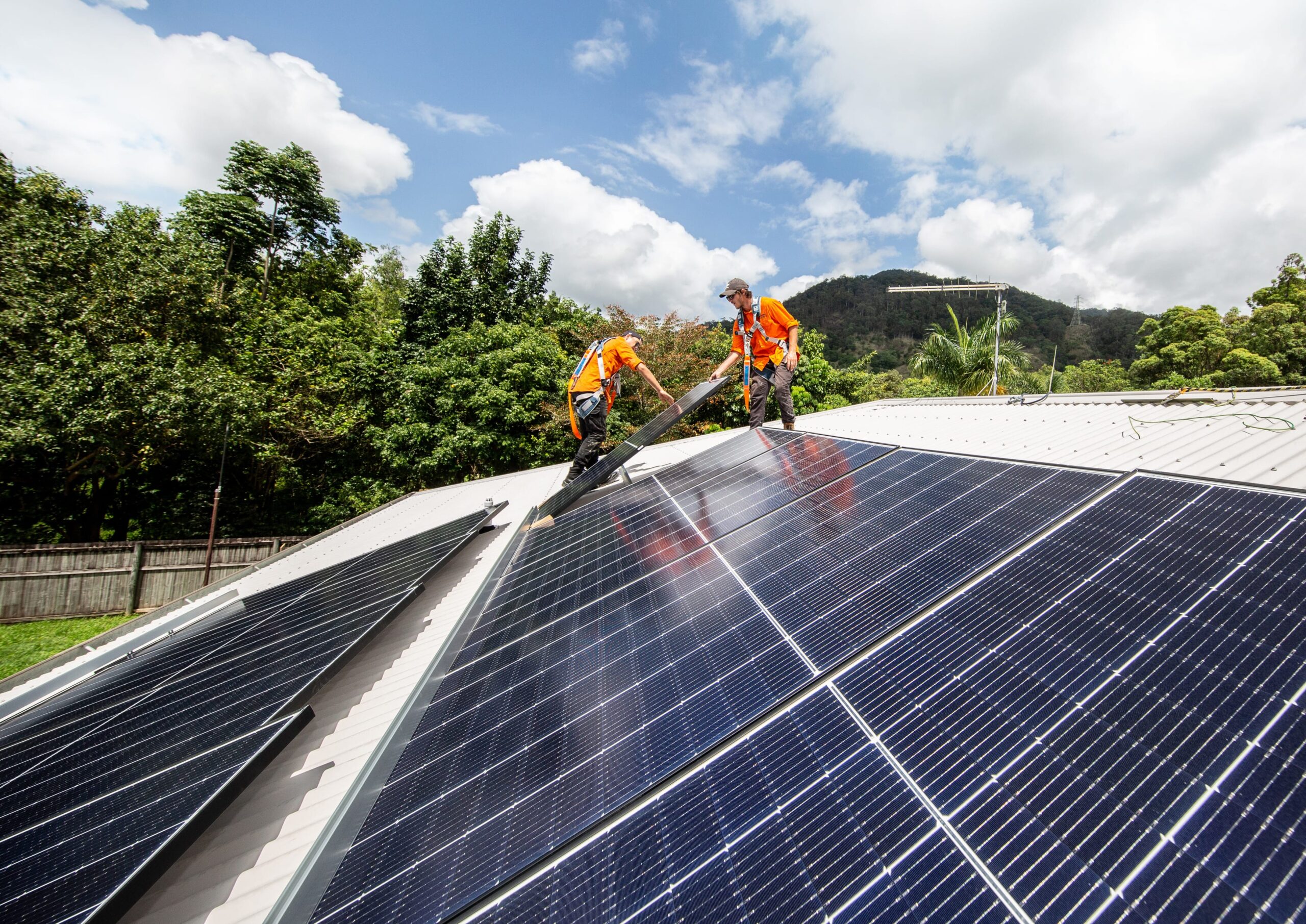 Two men working on solar panels on a roof in Cairns for Hielscher Electrical.