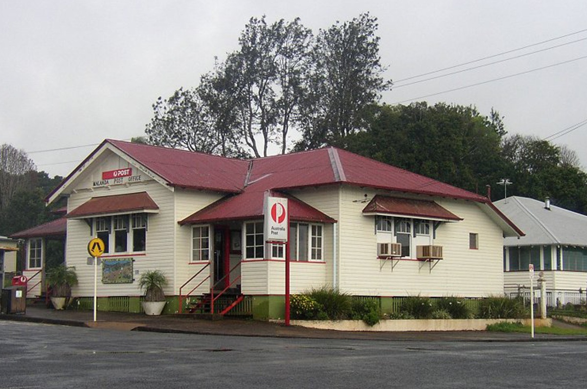 A white building with a red roof that incorporates solar panels provided by Hielscher Electrical.