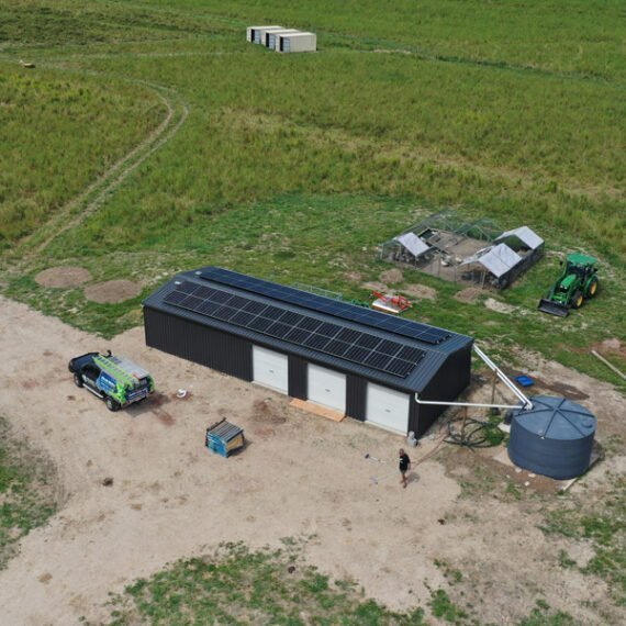 An aerial view of a solar farm in the middle of a field, featuring rows upon rows of solar panels.