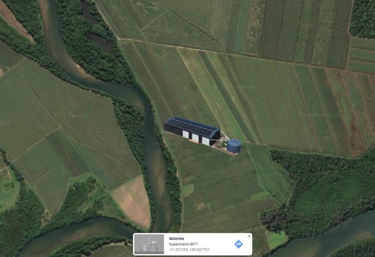 A satellite image of a house with solar panels in a field.