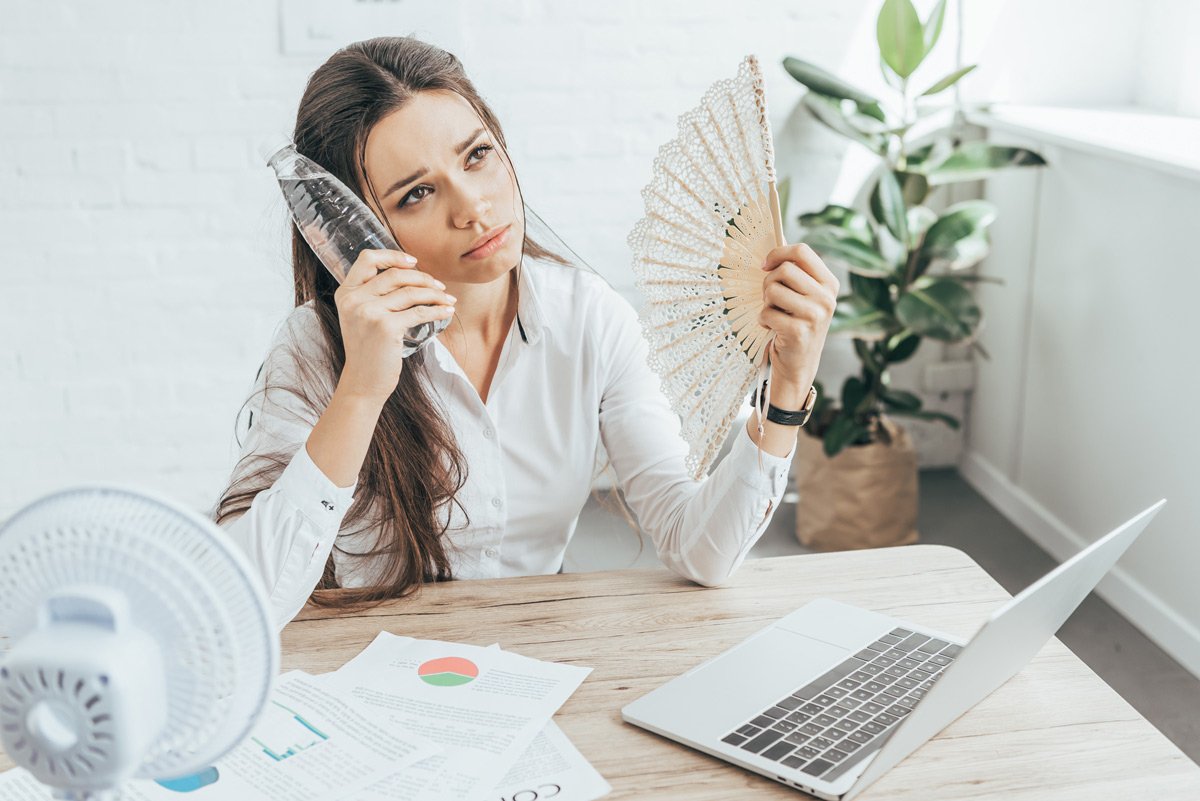 A woman holding a fan while talking on the phone is unaware of the potential benefits of solar power.