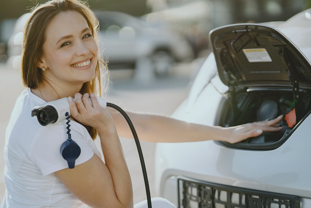 A woman is charging her car with solar power using a hose in Cairns.