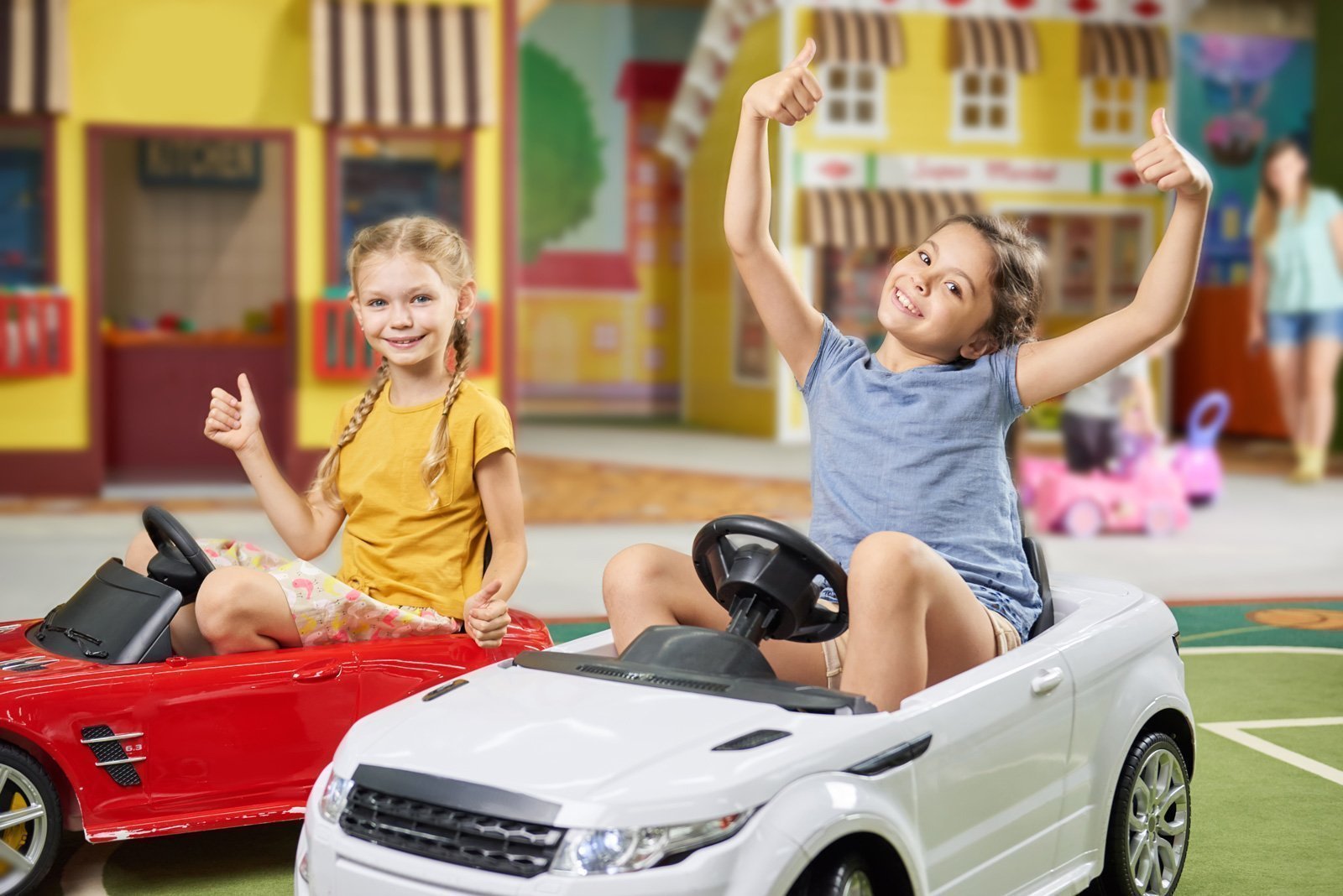 Two girls in toy cars exploring a toy store.