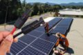 A person is holding a wire on a solar panel in Cairns.