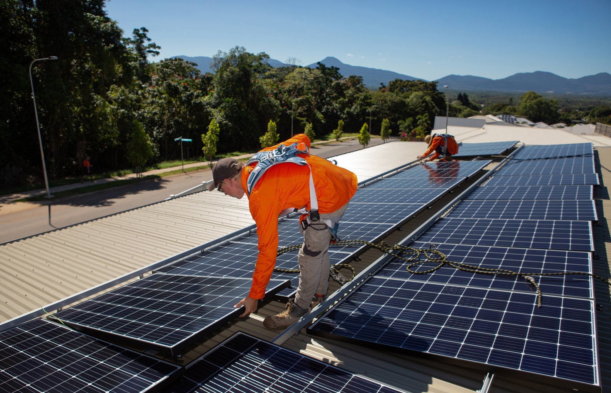 Two men from Hielscher Electrical working on solar panels on a roof.