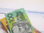 A stack of Australian dollars on top of an electricity account with Solar Power.