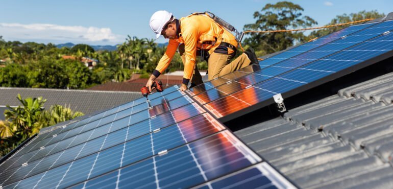 A worker from Hielscher Electrical is installing solar panels on a roof in Cairns.