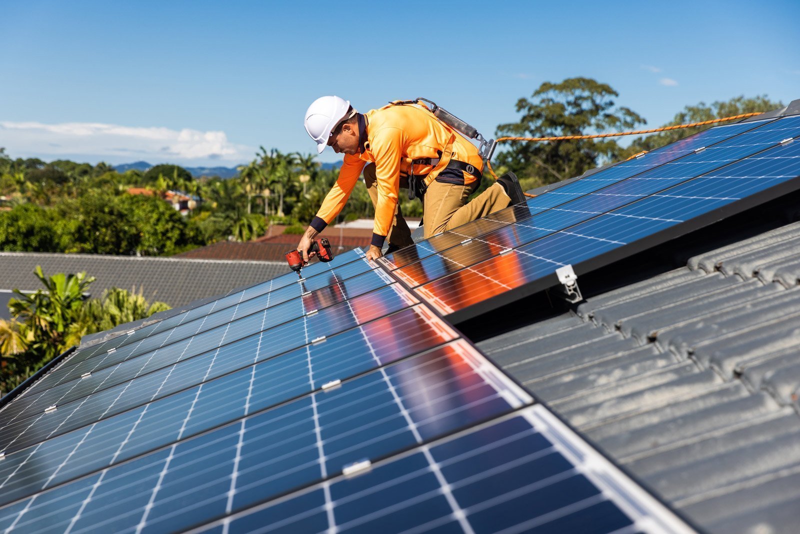 A worker from Hielscher Electrical is installing solar panels on a roof in Cairns.