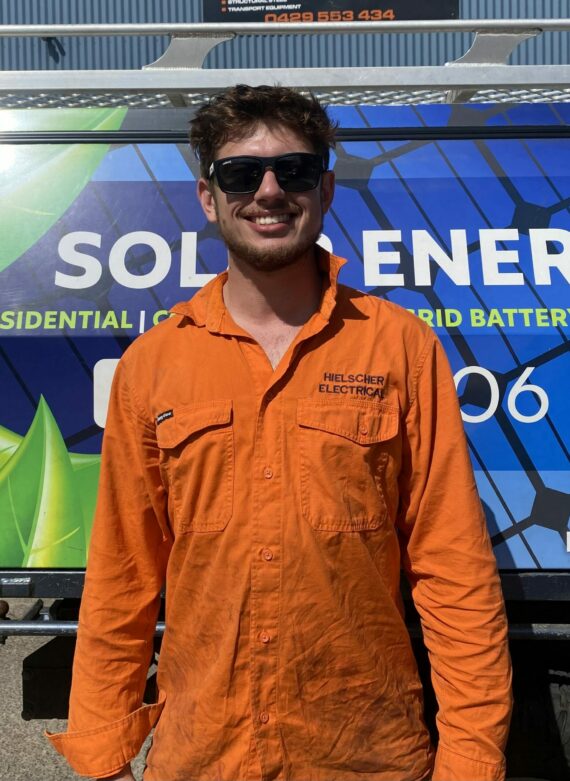 A man in an orange shirt standing in front of a solar energy truck promoting Solar Power.