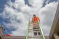 A man from Hielscher Electrical standing on a ladder installing solar panels.