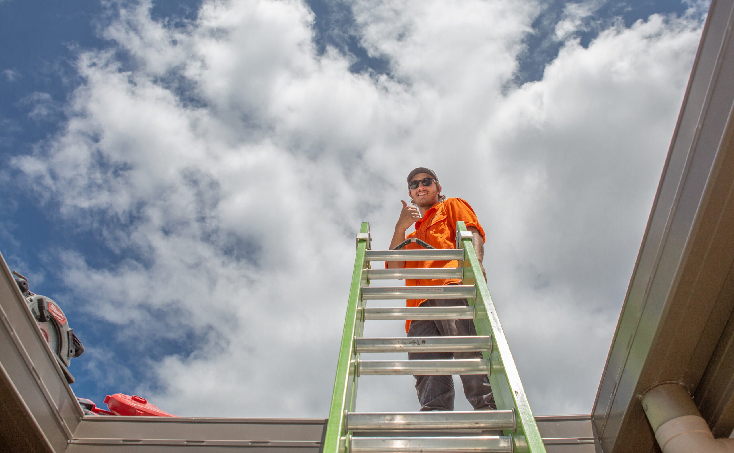 A man from Hielscher Electrical standing on a ladder installing solar panels.