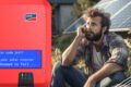 A man is sitting in front of a red solar inverter at Hielscher Electrical in Cairns.