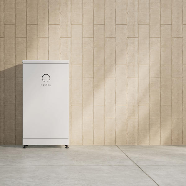 An 10kWh Sonnen Batterie Evo stands against a beige textured concrete wall in a well-lit space.