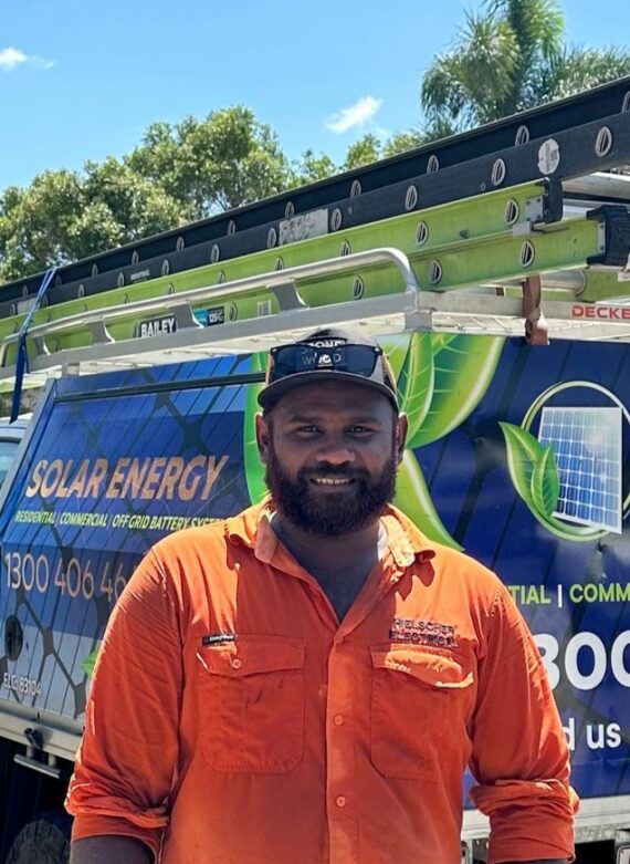 Man and his team in orange shirts standing in front of a van with solar energy service advertisements, under a sunny sky.