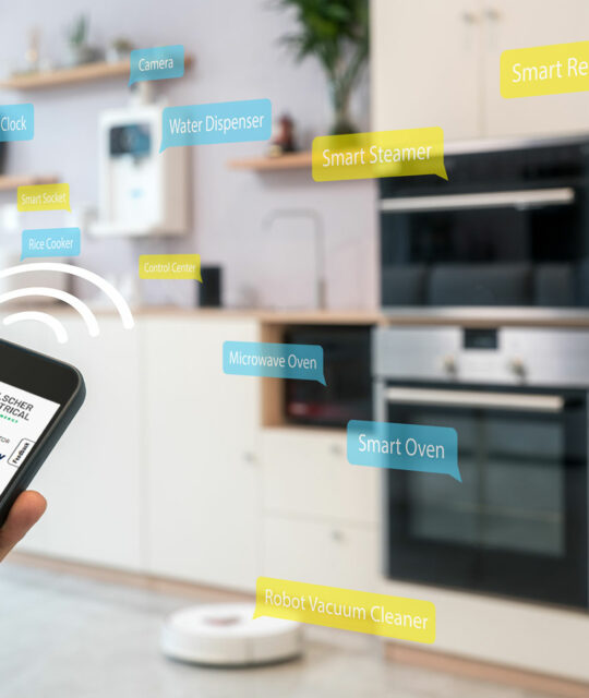 A person holds a smartphone displaying an appliance efficiency certification; in the background, various smart appliances in Cairns are labeled, including an oven, refrigerator, and more.