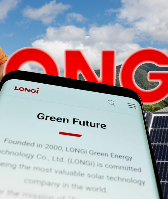 A man stands near solar panels with the lush mountains of Far North Queensland in the background; a phone displays LONGi’s website and commitment to green energy—highlighting LONGi Solar Cairns. The word "LONGI" appears prominently in bold letters.