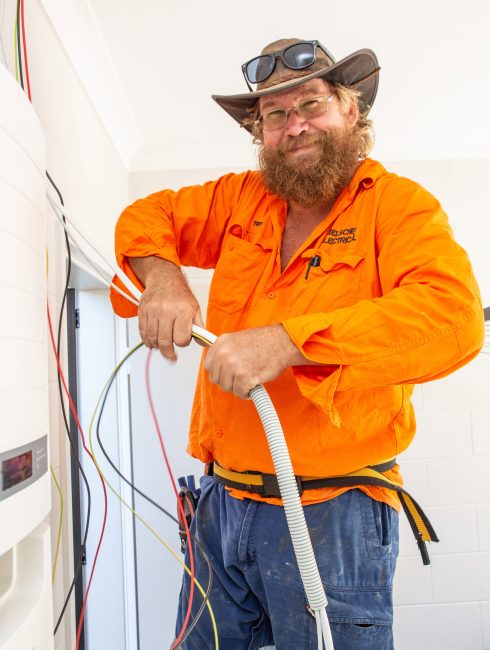 A man in an orange hat is working on a water heater powered by solar energy.