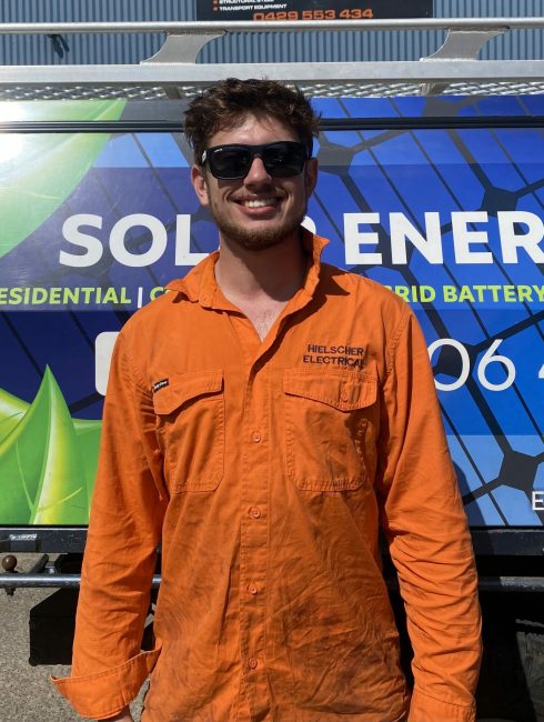 A man in an orange shirt standing in front of a solar energy truck promoting Solar Power.